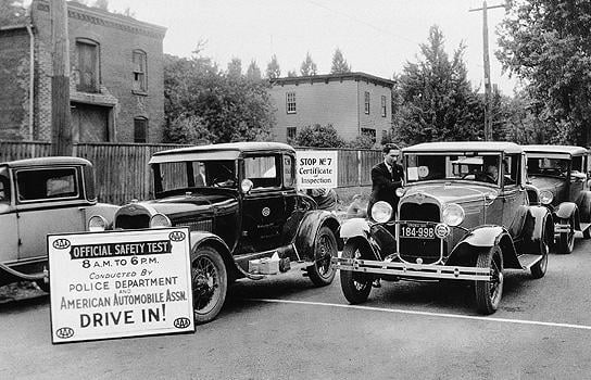 Historical photo of automobiles lined up for a safety inspection sponsored by local law enforcement and AAA